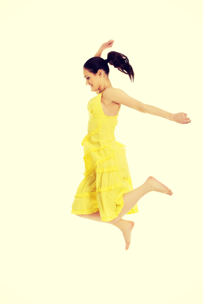 Beautiful woman jumping in yellow dress. - Photo, Image