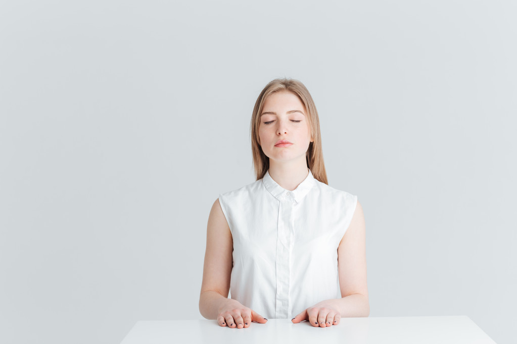 Zrelaksowany kobieta z zamkniętymi oczami siedząc przy stole - Zdjęcie, obraz
