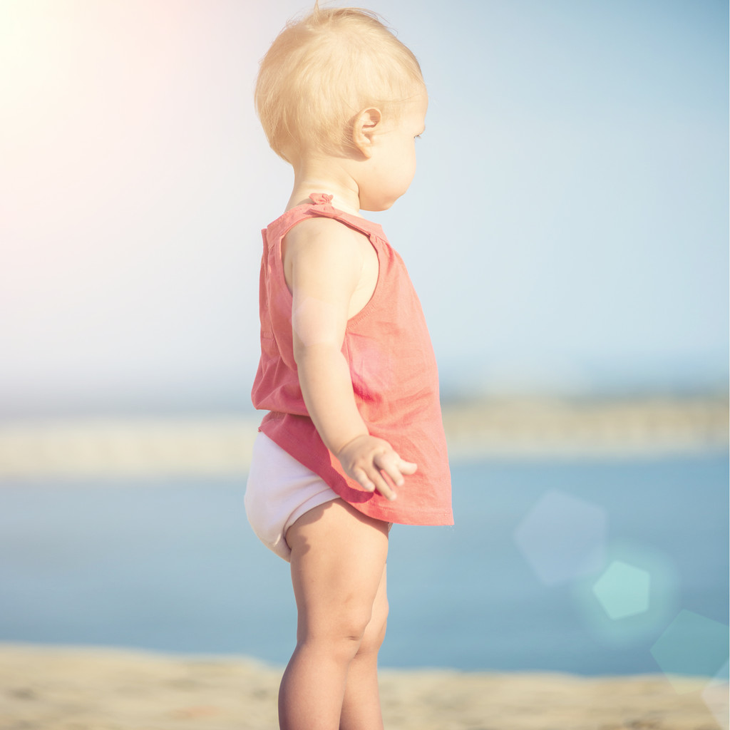 Menina bebê em vestido vermelho jogando na praia de areia perto do mar
. - Foto, Imagem