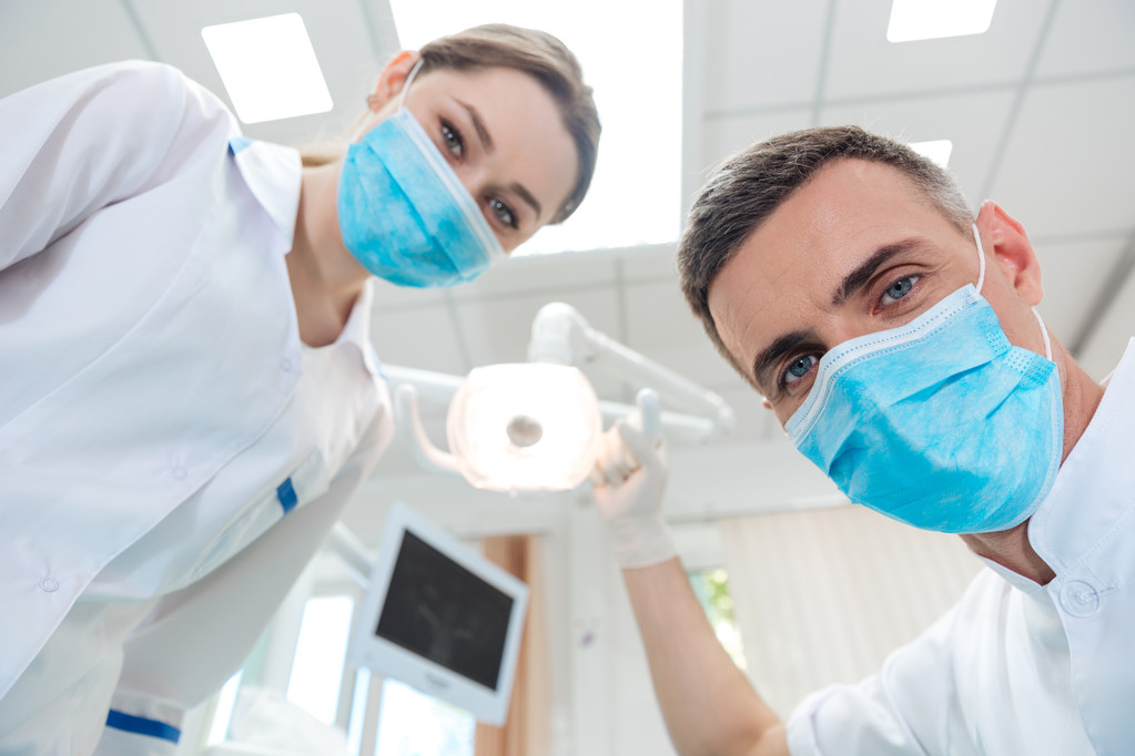 Dois dentistas fazendo tratamento odontológico para um paciente
 - Foto, Imagem