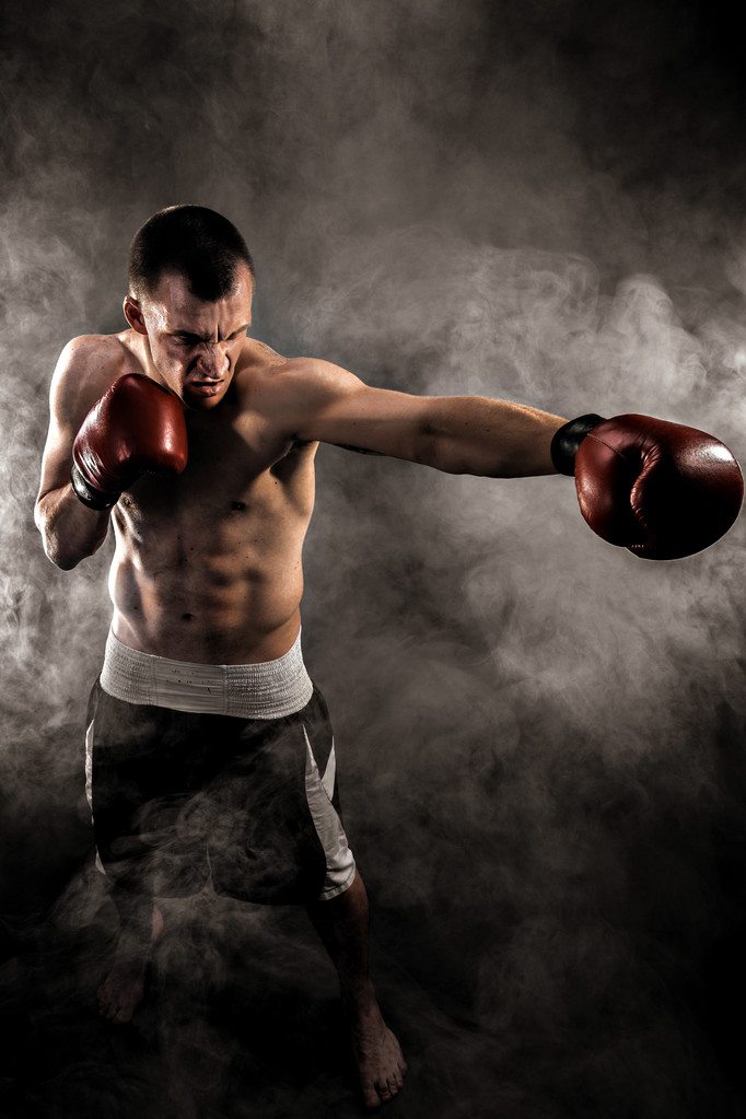 Muscular kickbox o muay thai luchador puñetazos en el humo
. - Foto, imagen