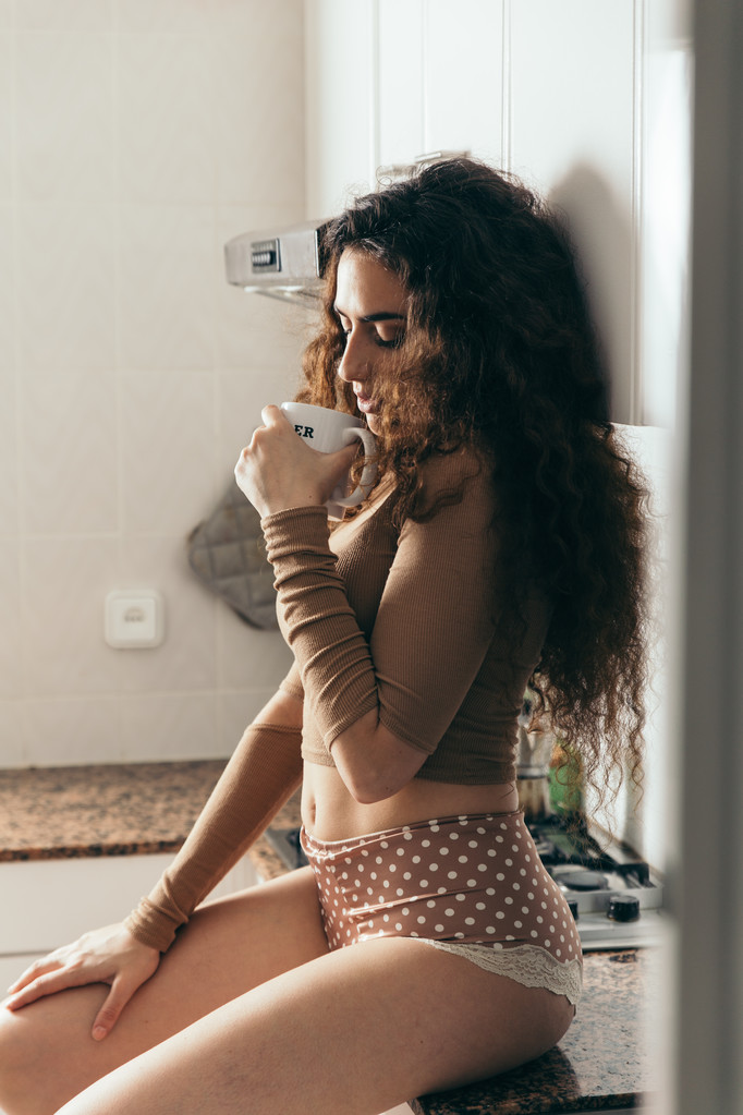 sexy Frau trägt Dessous und hält eine Kaffeetasse. - Foto, Bild