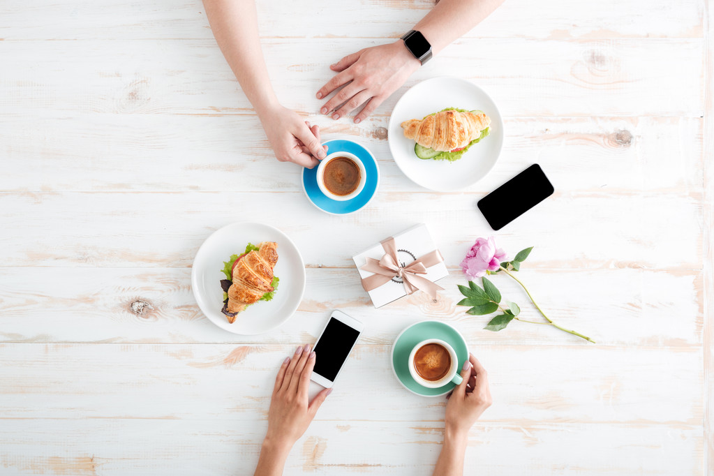 Mãos de homem e mulher tomando café da manhã na mesa de madeira
 - Foto, Imagem