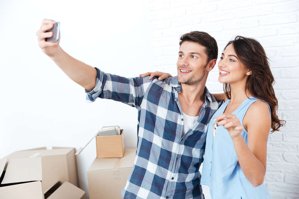 Young couple making selfie holding keys in new flat - Photo, Image
