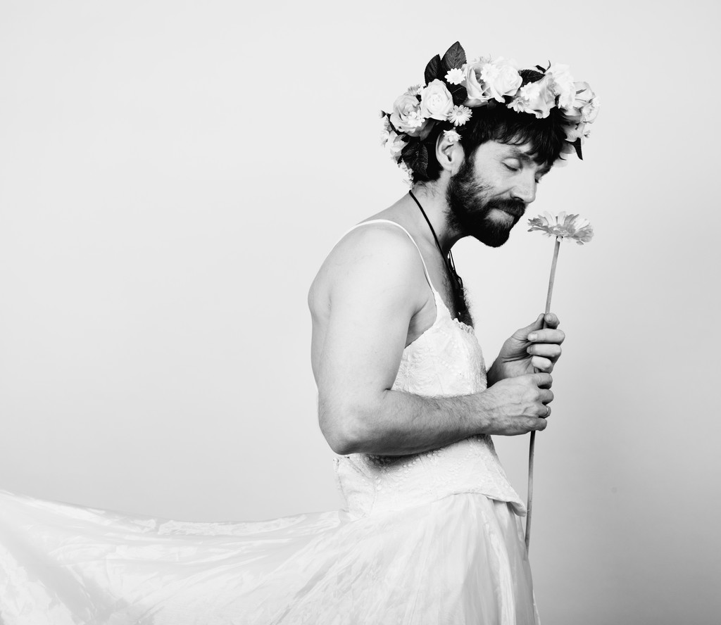 бородатий чоловік у жіночій весільній сукні на її оголеному тілі, тримає квітку. на голові вінок з квітів. смішна бородата наречена, чорно-біла
 - Фото, зображення