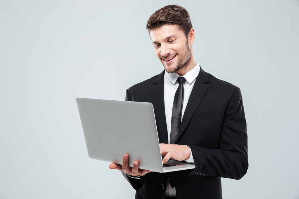 Giovane uomo d'affari allegro sorridente e utilizzando il computer portatile
 - Foto, immagini