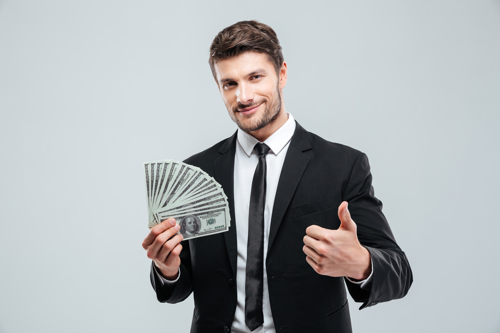 Sorrindo jovem empresário segurando dinheiro e mostrando polegares para cima
 - Foto, Imagem