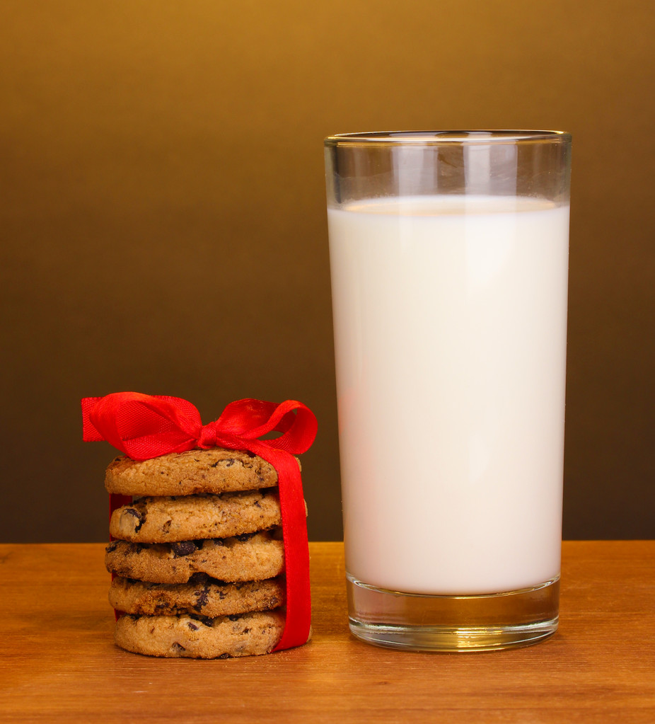 szklankę mleka i ciasteczka na drewnianym stole na brązowym tle - Zdjęcie, obraz