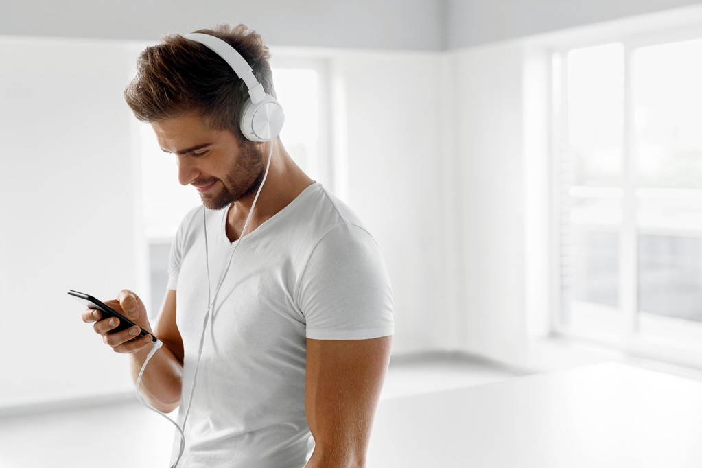 Música Escuchando. Hombre en auriculares usando teléfono móvil en interiores
 - Foto, imagen