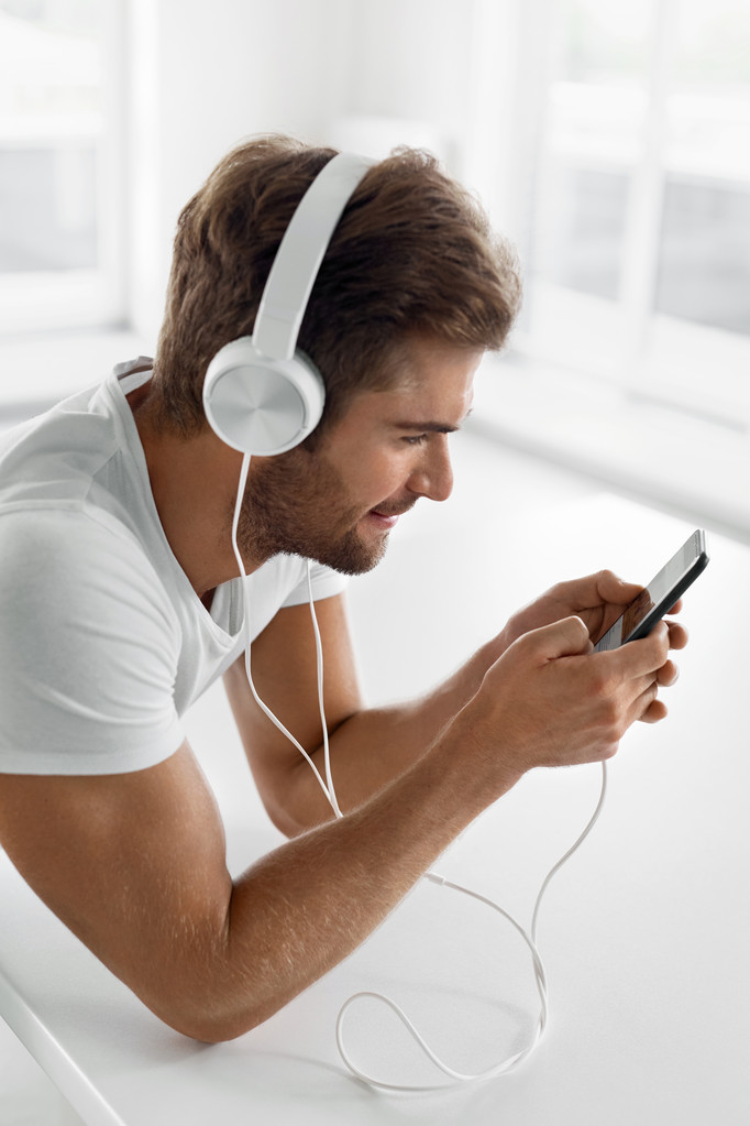 Musikhören. Mann mit Kopfhörer benutzt Handy im Haus - Foto, Bild