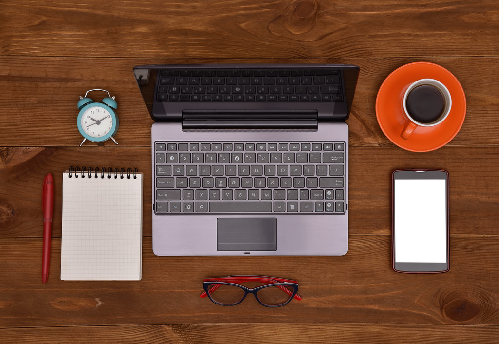 laptop, celular, óculos, bloco de notas e xícara de café na mesa de madeira
 - Foto, Imagem