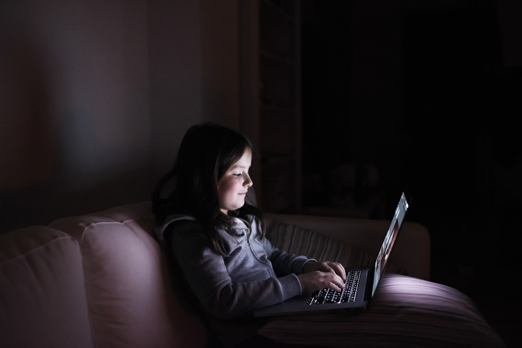 Menina, sentada no escuro, brincando com o laptop
 - Foto, Imagem