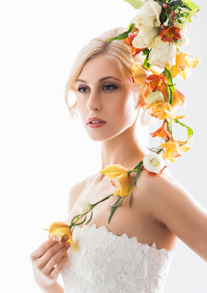 Portrait d'une jeune mariée en robe blanche posant avec des fleurs
 - Photo, image
