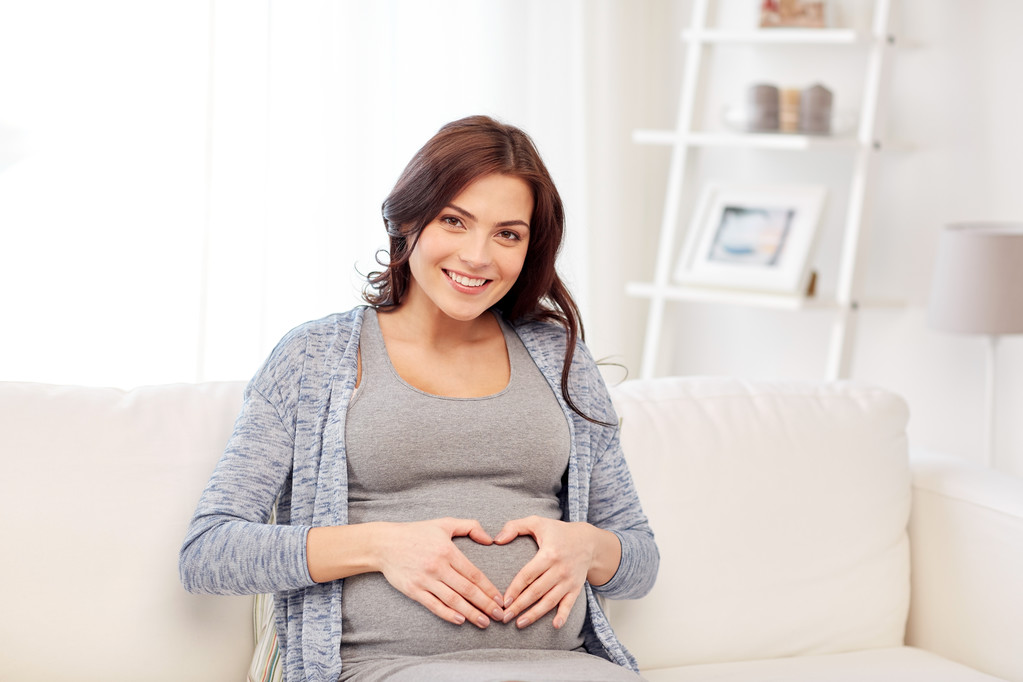 mulher grávida feliz fazendo gesto de coração em casa
 - Foto, Imagem