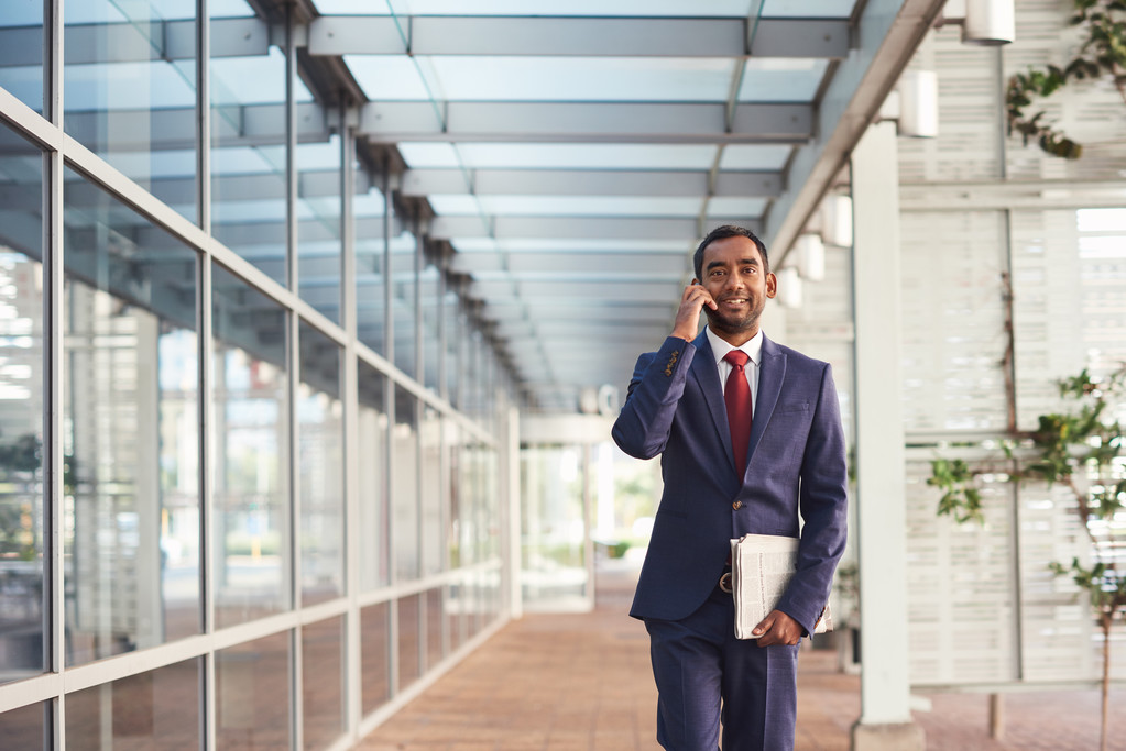 бізнесмен розмовляє на мобільному телефоні під час ходьби
 - Фото, зображення