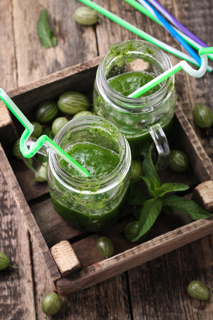 Verse groene smoothie met rietjes op een houten tafel, gezond veganistisch eten - Foto, afbeelding
