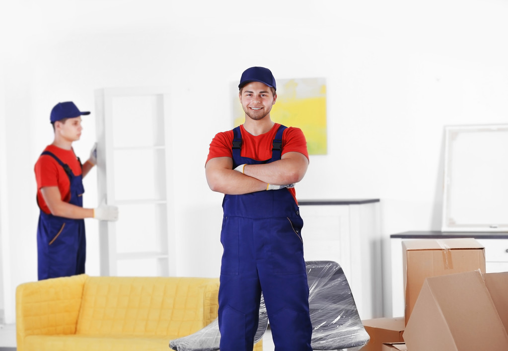 männliche Arbeiter mit Kisten und Möbeln im neuen Haus - Foto, Bild