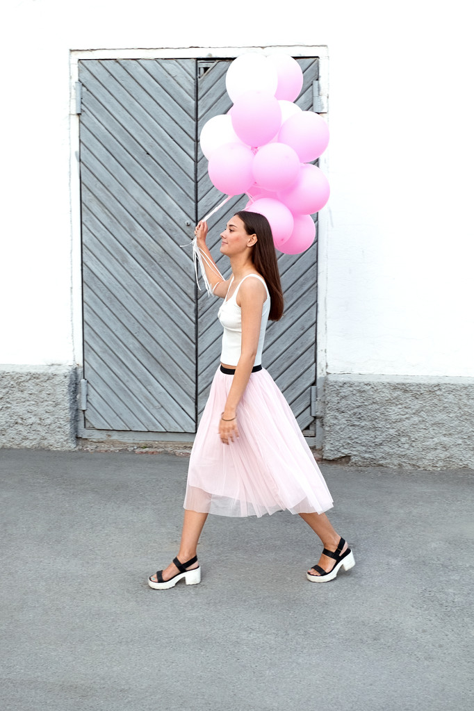 Widok z boku z brunetka dziewczyna odchodzisz z różowy balony na ulicy - Zdjęcie, obraz
