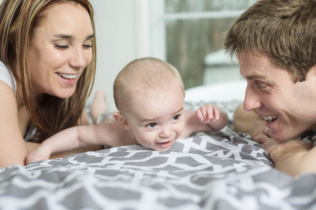 幸せな家族の父親、母親と赤ちゃんのベッドで遊ぶ - 写真・画像