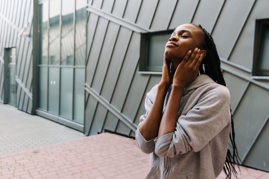 Životní styl a lidé koncept - úsměvem africké americké mladá žena nebo dospívající dívka ve sluchátkách poslouchat hudbu zavírání uši rukama venku - Fotografie, Obrázek
