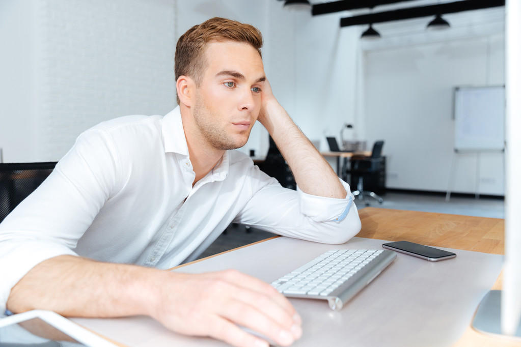 Triste jeune homme d'affaires ennuyé travaillant avec l'ordinateur dans le bureau
 - Photo, image