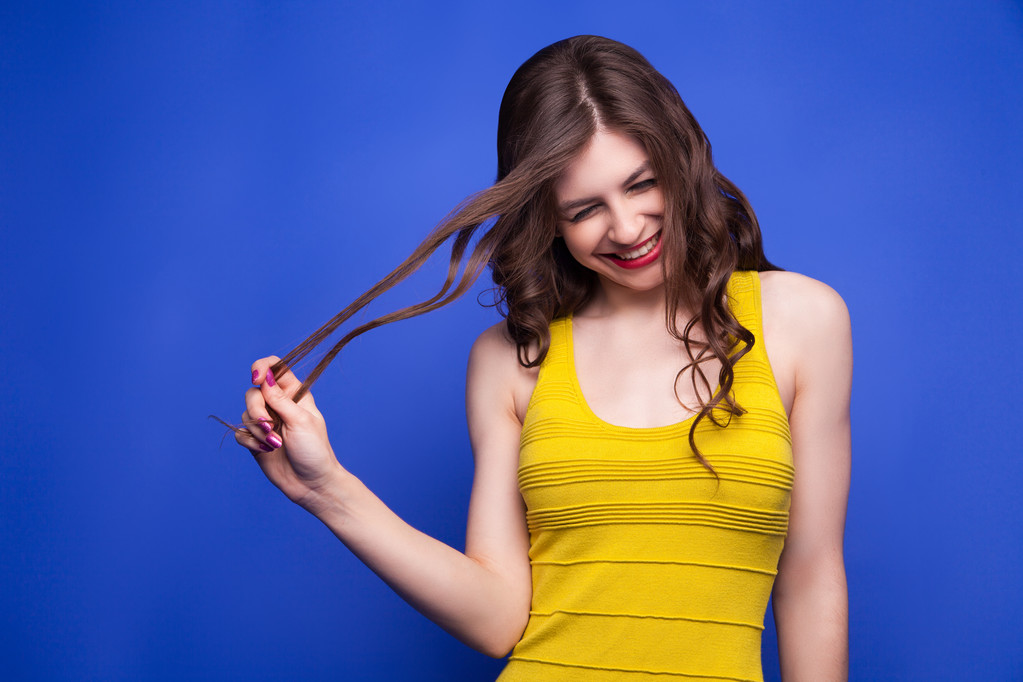 Весела модель в жовтій сукні тягне за волосся
 - Фото, зображення