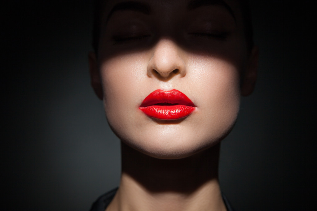 Hermoso modelo con labios de color rojo brillante y la cara medio cubierto de sombra
 - Foto, imagen