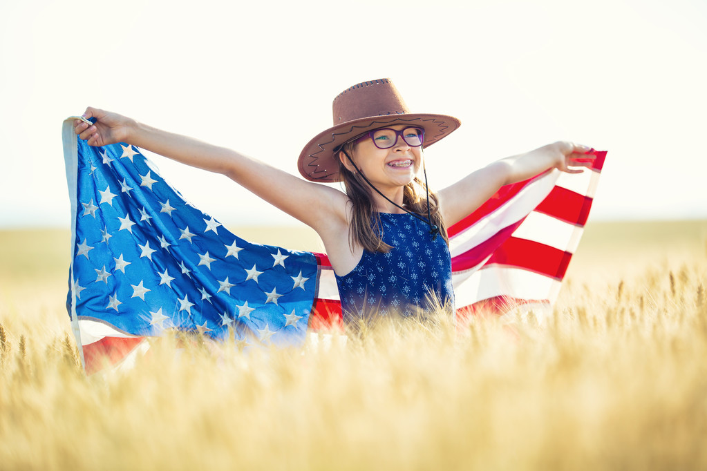 Dość młoda pre-teen dziewczyna z American kowbojski kapelusz w polu kukurydzy i gospodarstwa Flaga Amerykańska - Zdjęcie, obraz