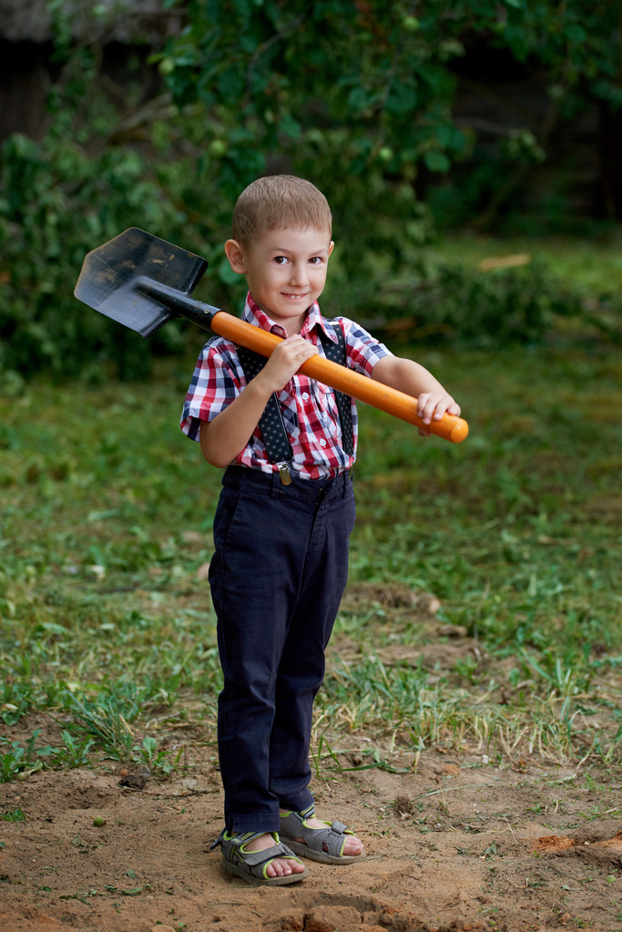 grappige jongen met de schop in de tuin - Foto, afbeelding