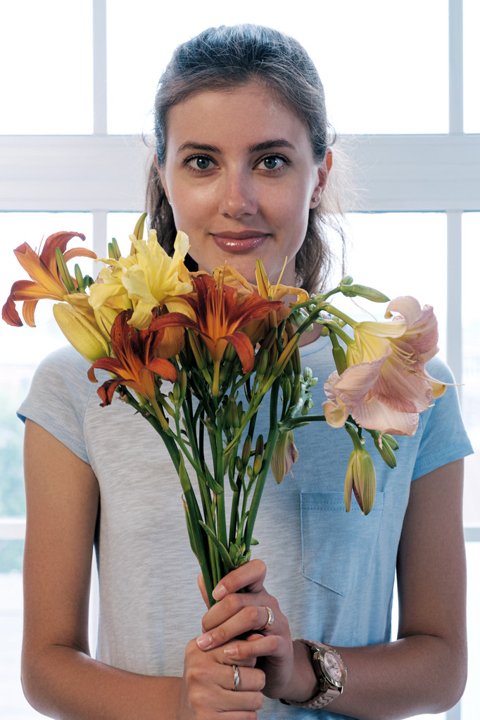 Retrato de atractiva morena con ramo de flores aromáticas de colores contra de ventana
 - Foto, Imagen