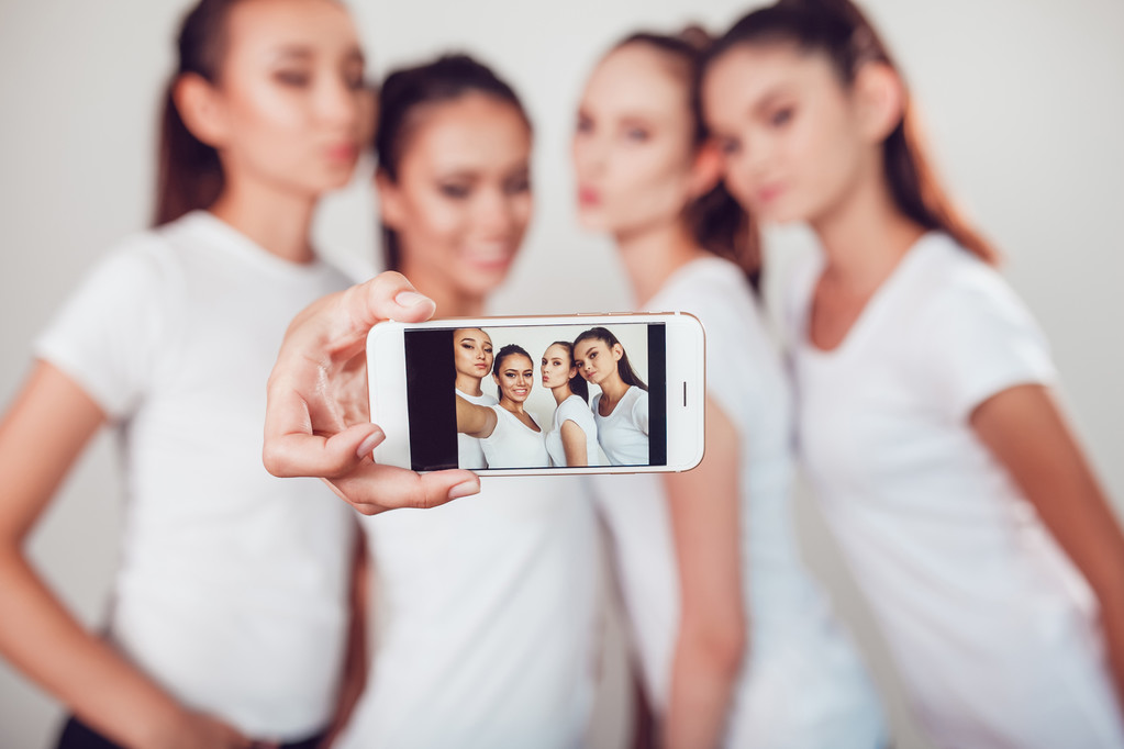 Positiiviset ystävät muotokuva neljä onnellista tyttöä tehdä selfie, varmasti hauskoja kasvoja, grimaces, iloa, tunteita, rento tyyli, pastellivärit, valkoinen seinä. Hullu hauska nainen. Valkoinen tausta
. - Valokuva, kuva
