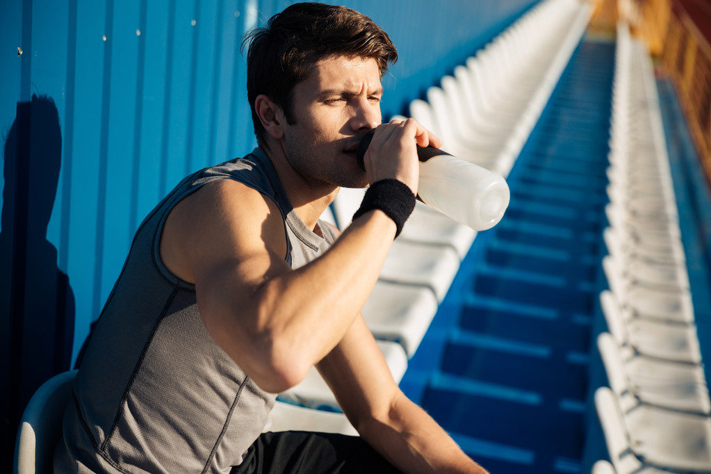 Young handsome male athlete drinking water after workout - Photo, Image
