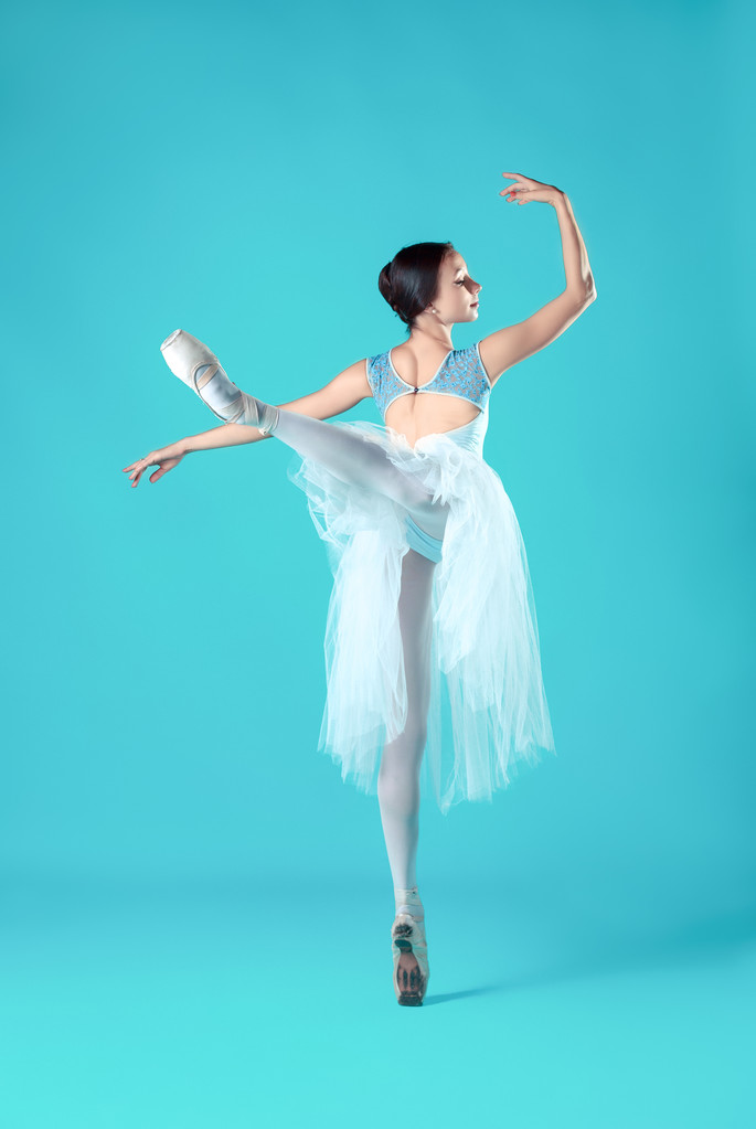 Bailarina en vestido blanco posando en los dedos de los pies, fondo del estudio
. - Foto, imagen