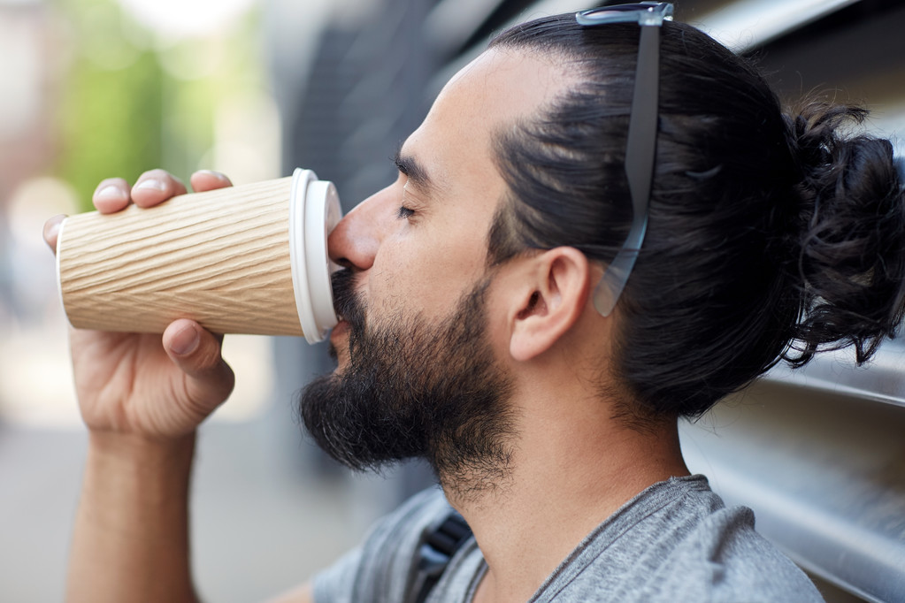 man drinking coffee from paper cup on street - Photo, Image