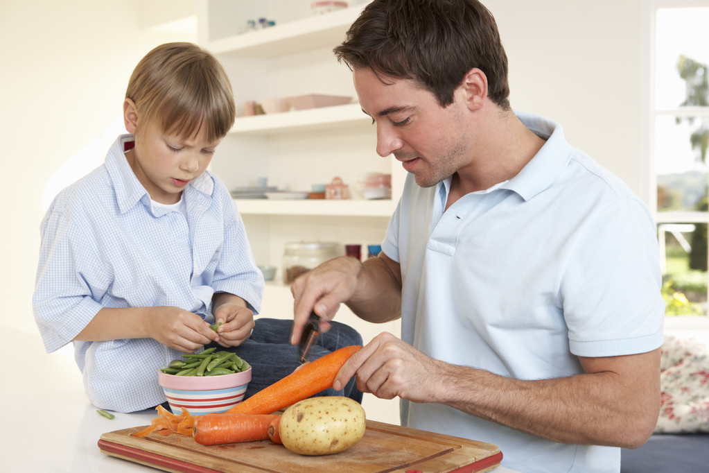 台所で野菜を剥離少年と幸せな若い男 - 写真・画像