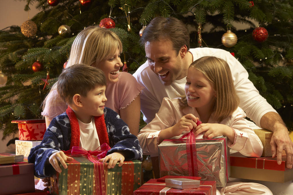 Семья открывает рождественский подарок перед Три
 - Фото, изображение