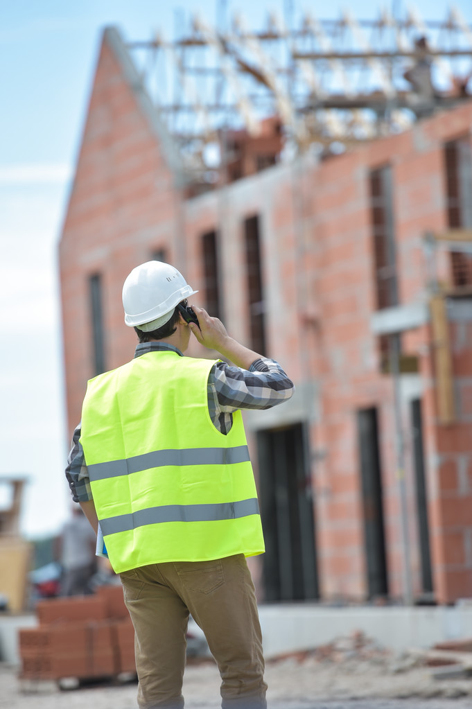 Foreman walking using walkie-talkie on construction site - Photo, Image