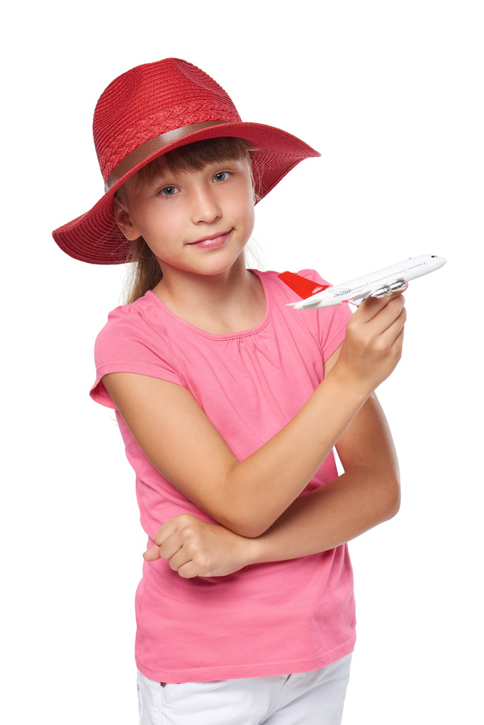 reizendes kleines Mädchen mit Touristenmütze und kleinem Flugzeugspielzeug - Foto, Bild