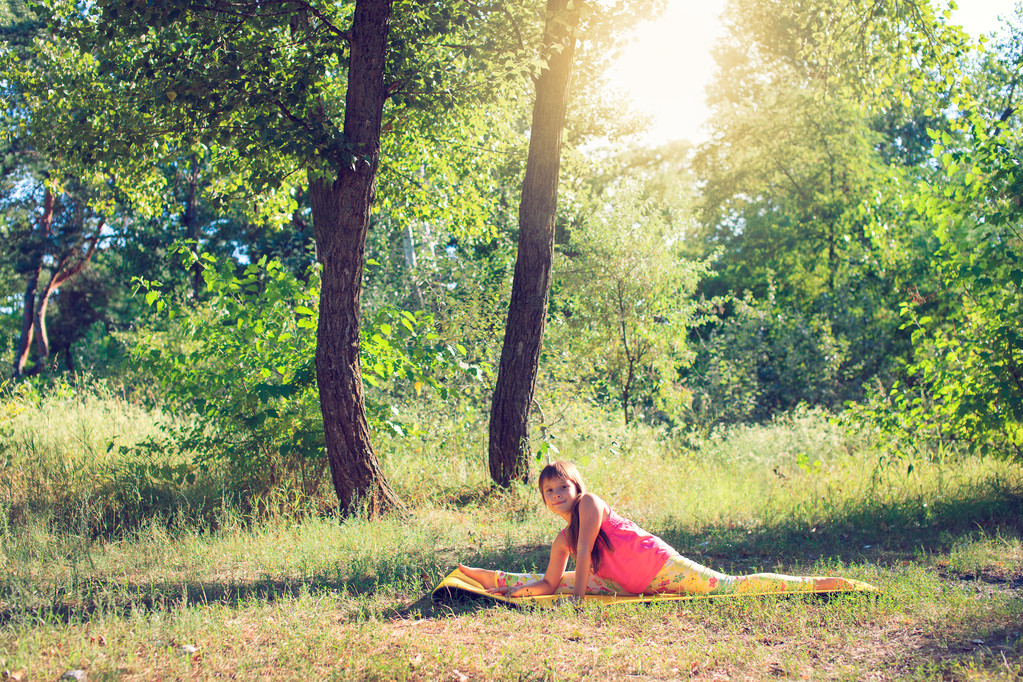 Tiener yoga doen en ontspannen door plaatsing in een gras in een park - Foto, afbeelding