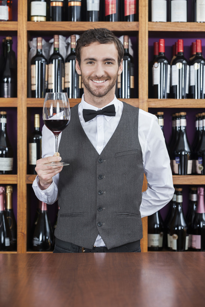 Barman, trzymając kieliszek do wina w kasie - Zdjęcie, obraz