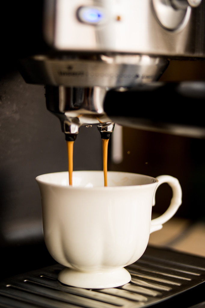 espressomachine maken van koffie en gieten in een witte kop - Foto, afbeelding