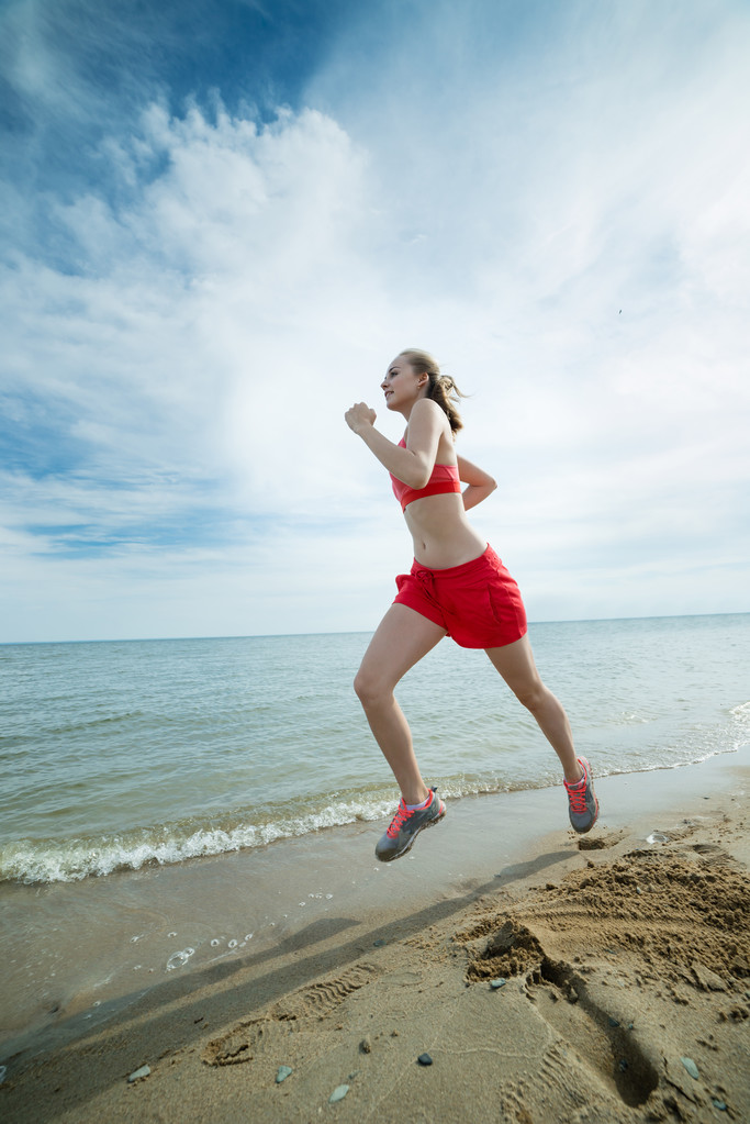 junge Frau läuft am sonnigen Sommer-Sandstrand. Training. Joggen - Foto, Bild