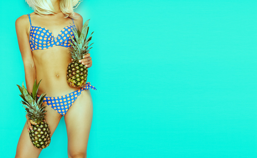 gebräunte Blondine mit Ananas auf blauem Hintergrund. polka dot swi - Foto, Bild