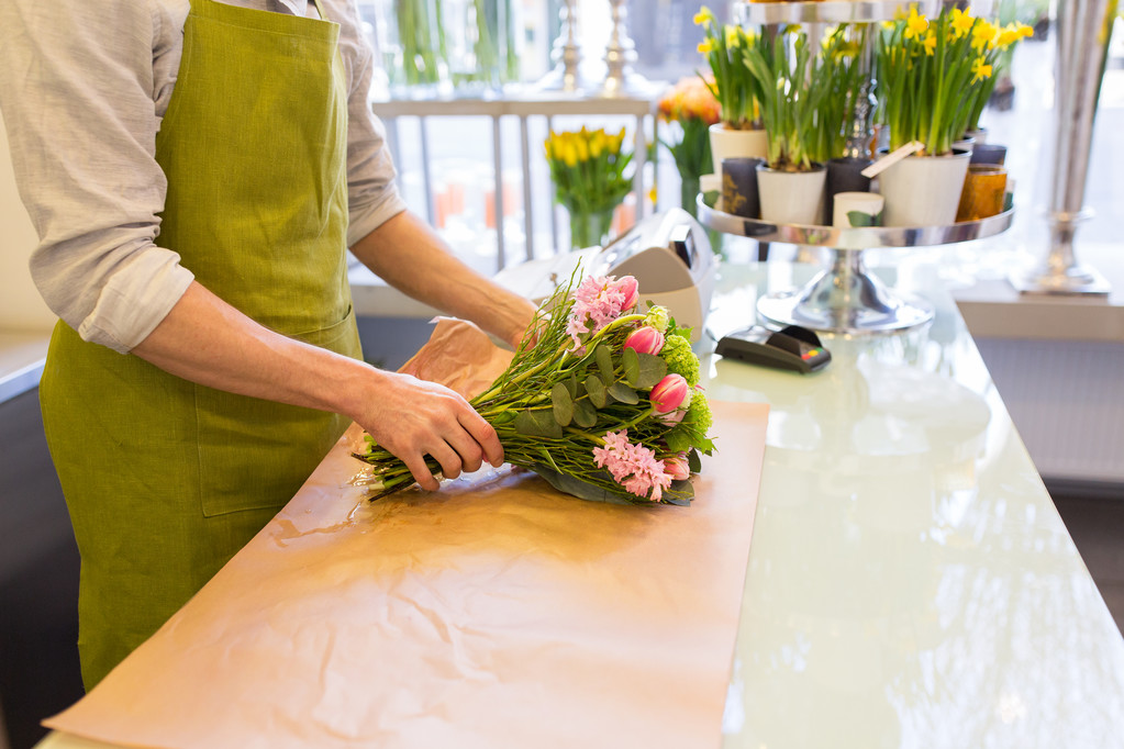 цветочник заворачивает цветы в бумагу в цветочном магазине
 - Фото, изображение