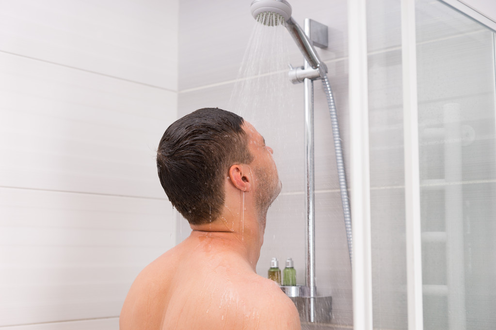 Молодий чоловік приймає душ у ванній
 - Фото, зображення