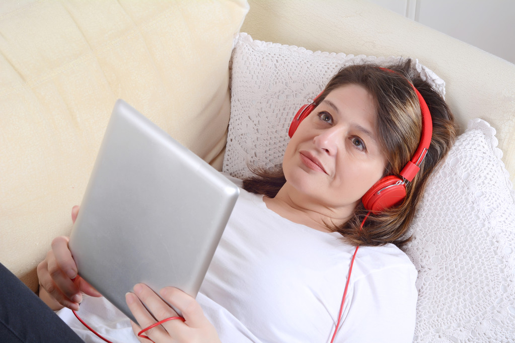Nainen kuuntelee musiikkia digitaalinen tabletti sohvalla
. - Valokuva, kuva