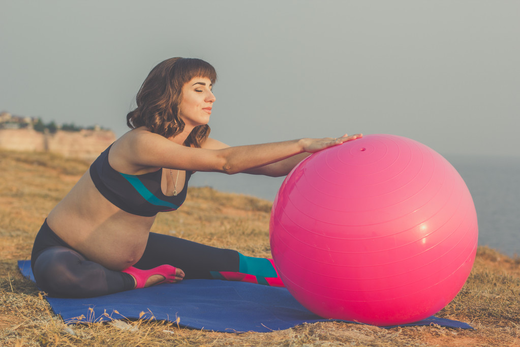 schwangere Mädchen mit rosa Fitball beim Stretching - Foto, Bild
