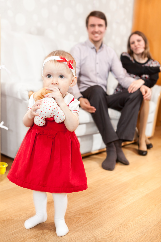 Ön planda ailesi arka planda olan güzel beyaz bir kız bebek. - Fotoğraf, Görsel