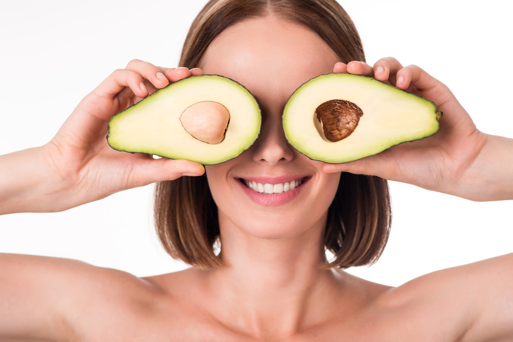 Mooie jonge vrouw bedrijf avocado - Foto, afbeelding