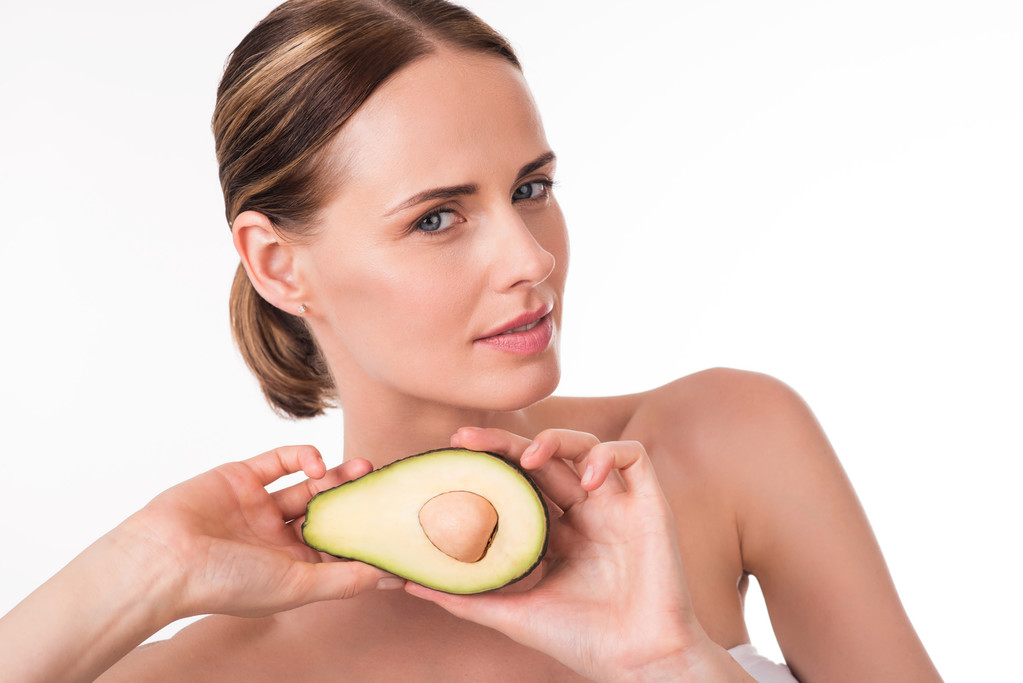 Aantrekkelijke jonge vrouw bedrijf avocado - Foto, afbeelding